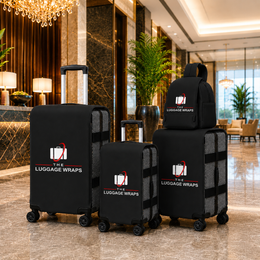 Trois enveloppes noires sur des valises à roulettes et un sac à dos assorti, exposé dans le hall d’un hôtel de luxe. Le nom de la marque « THE LUGGAGE WRAPS » est clairement imprimé sur chaque article.