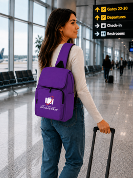 Une femme dans un terminal d’aéroport portant un sac à dos violet vif avec un logo blanc et rouge « LUGAGEWRAP » sur la poche avant, tout en tirant une valise noire à roulettes.